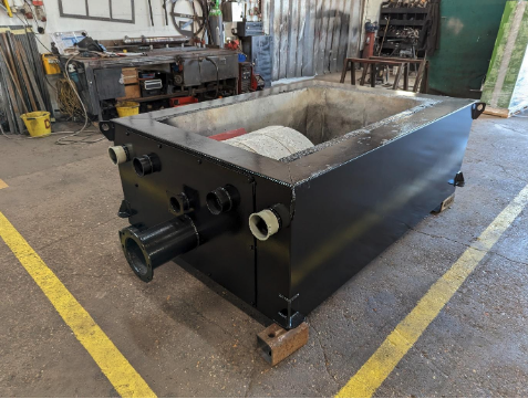 Factory view of Ranheat 300kW biomass boiler base with exposed retort and cast refractory walls.