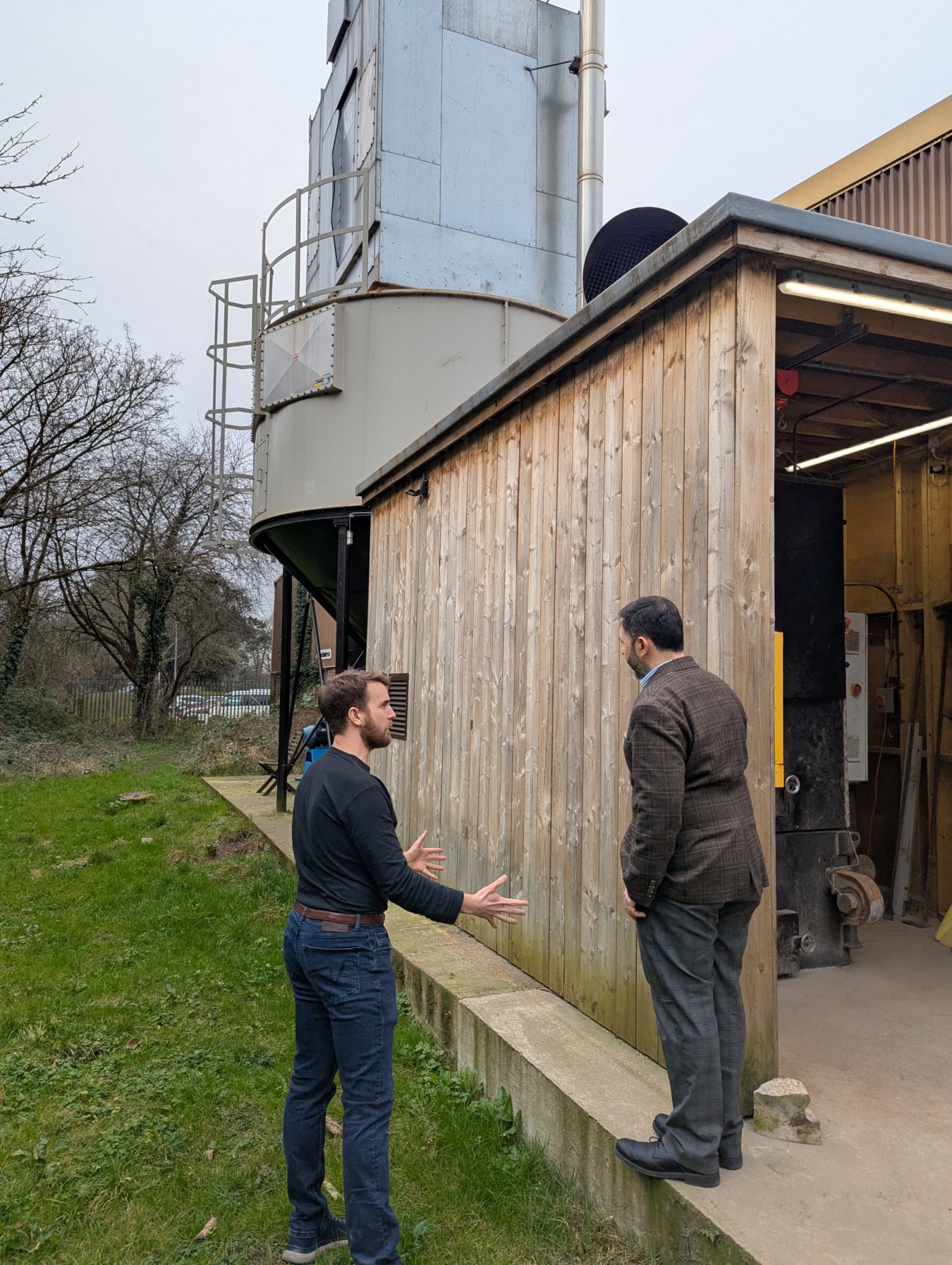 Ross Larner and Sadik Al-Hassan, MP of the United Kingdom, discussing the custom-built burner room at Paneltech, which houses the Ranheat WA 300 biomass heating system and connects to the C25 4m 1 Ring Industrial Wood Waste Silo.