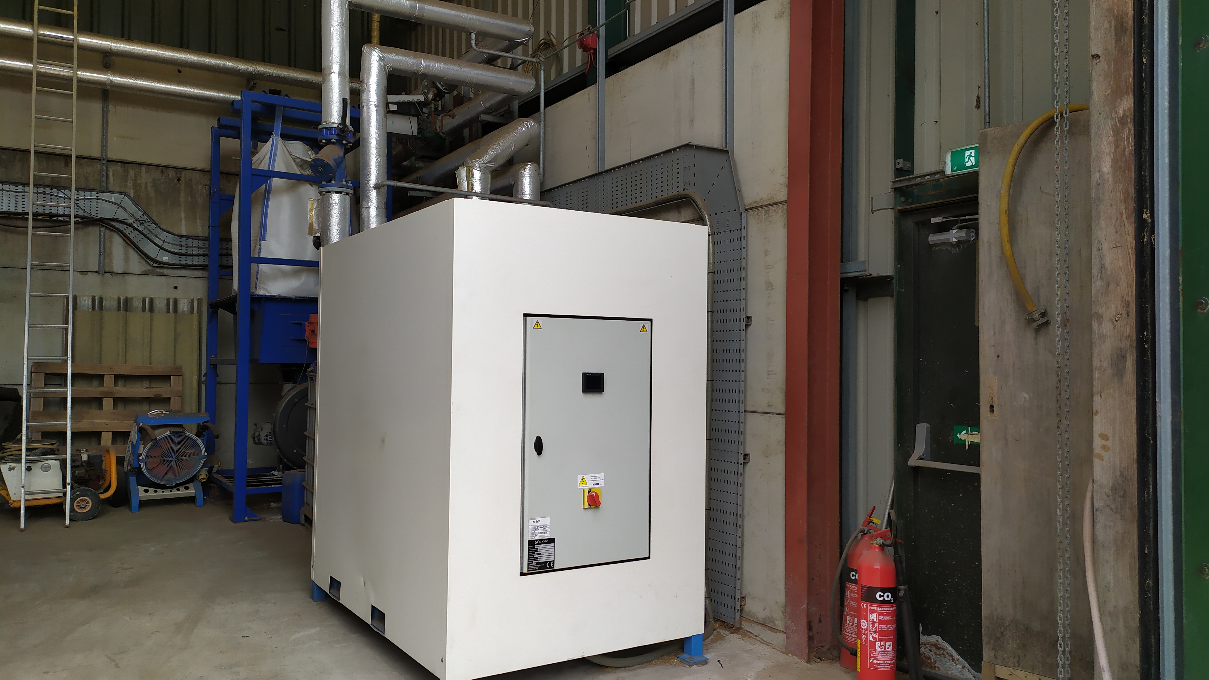 Front view of a 40kWe Organic Rankine Cycle (ORC) unit on its skid, connected to a Ranheat biomass boiler, showcasing electricity generation from hot water heating systems.